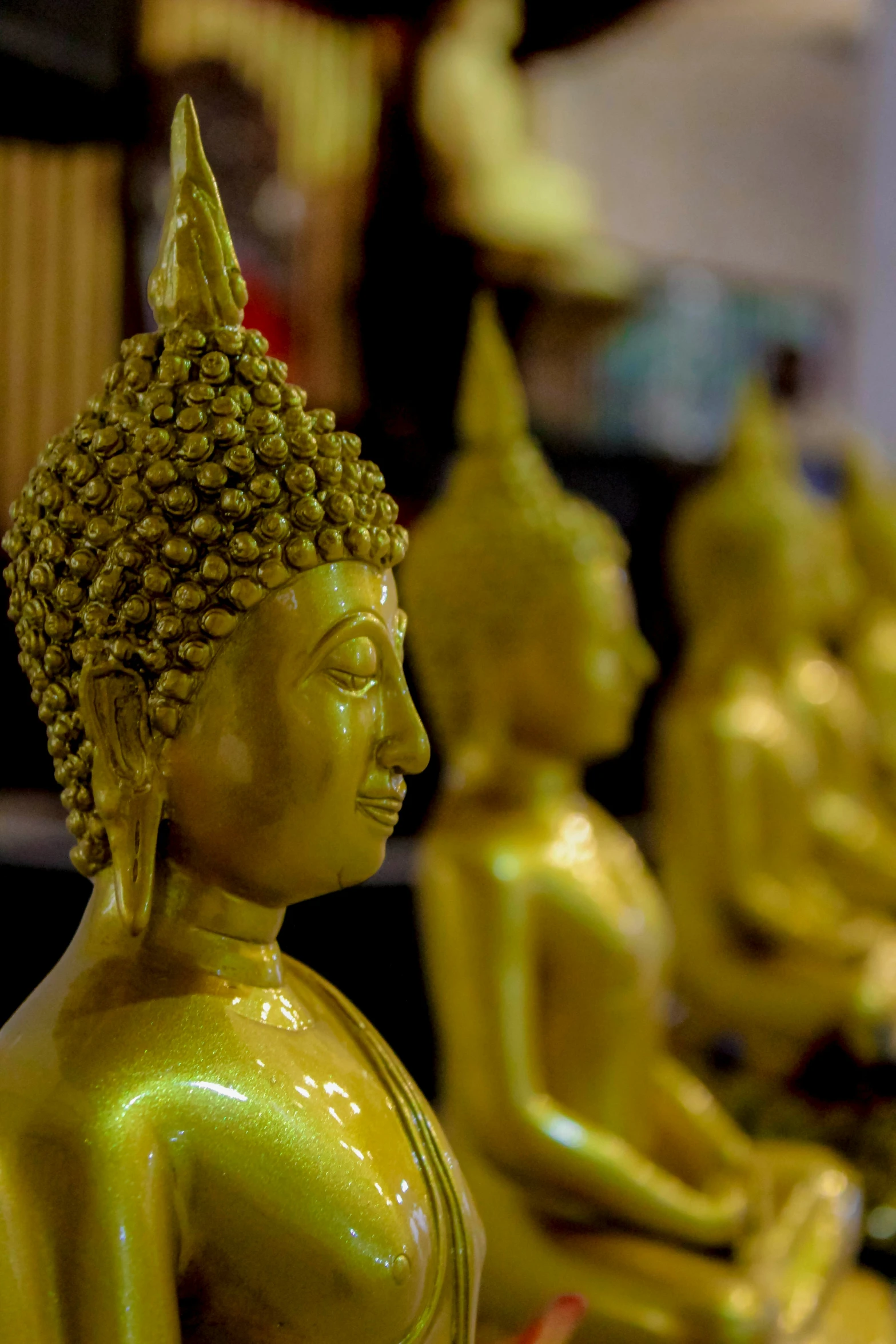 a row of buddha statues with gold colored finish