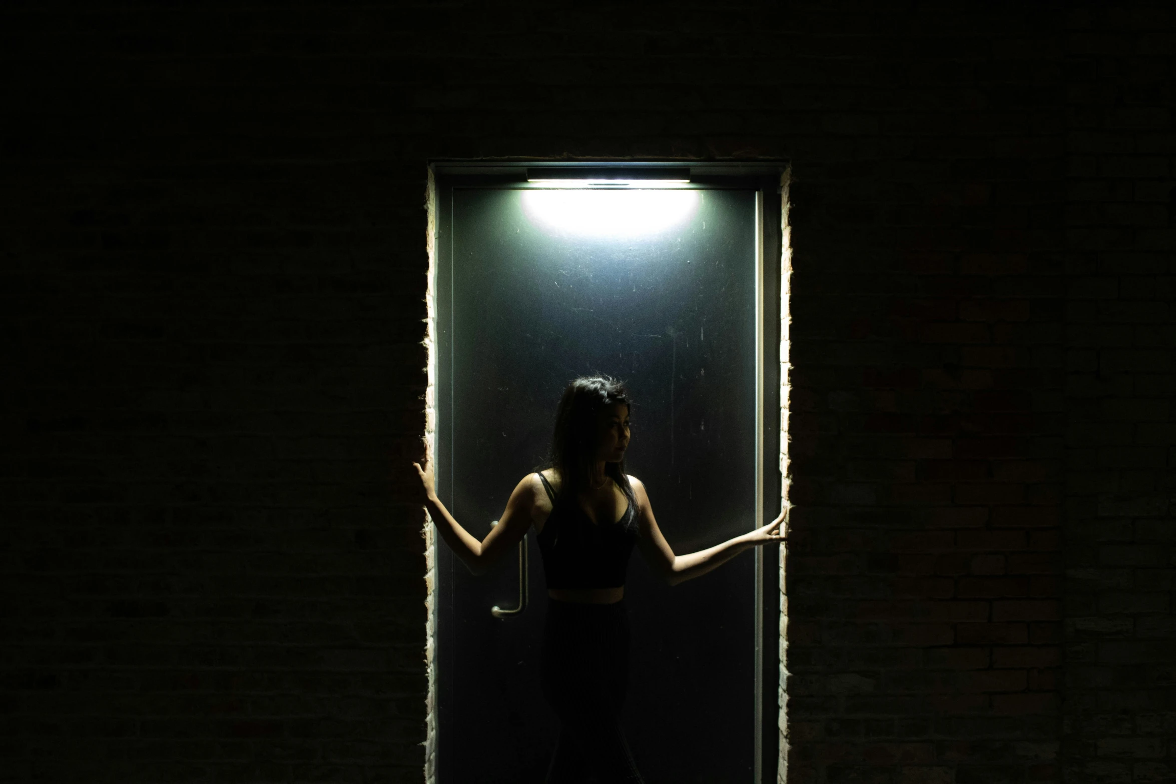 the woman is standing outside a doorway lit up by lighting