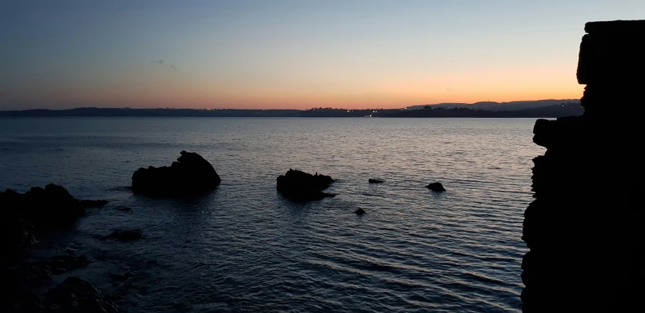 a sunset over the ocean and some rocks