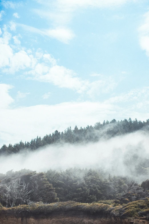 a plane flying over a hill with low clouds