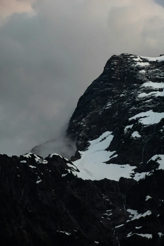 mountains covered in snow with clouds blowing across them