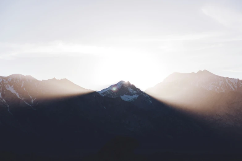 the sun shining on a mountain with a cloudy sky