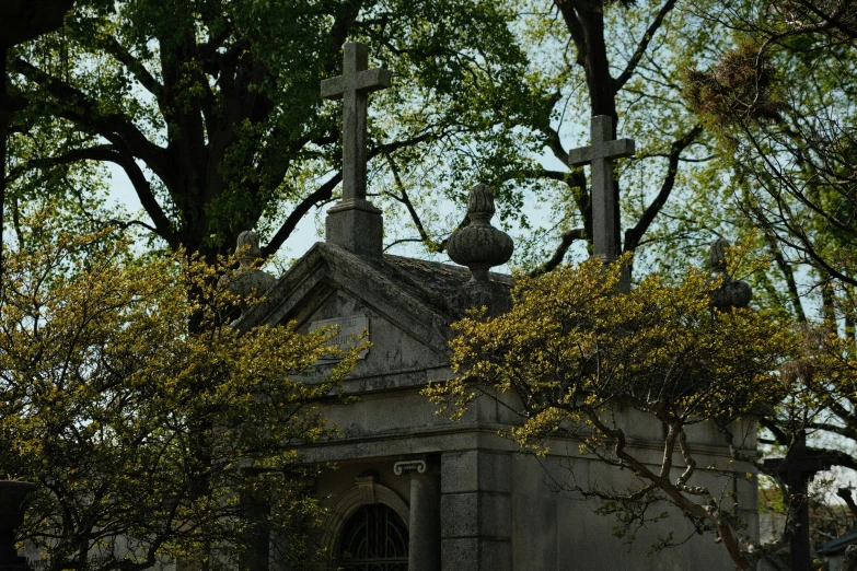 a small gray church with trees and a cross