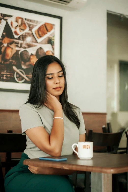 a woman sitting at a table holding a coffee mug