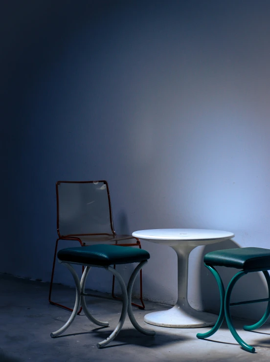two tables and chairs against a wall, one white table and the other green