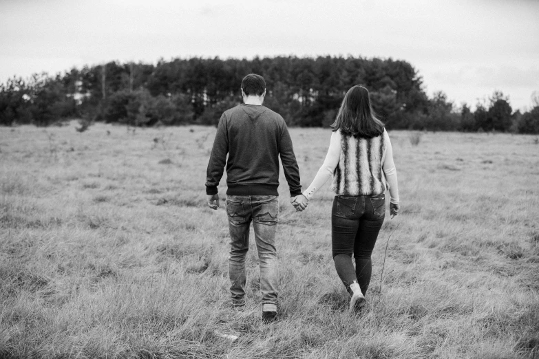 two people are walking through an empty field