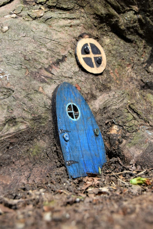 a blue toy on a tree trunk with another one laying underneath it