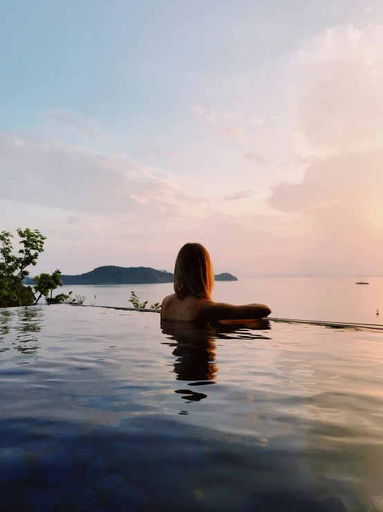 a woman laying in a large swimming pool at sunset