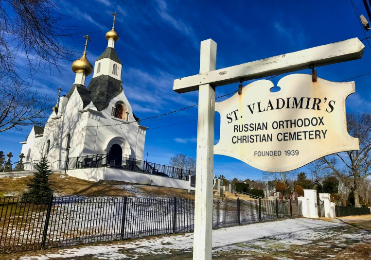 a white building has a sign with a gold and silver cross