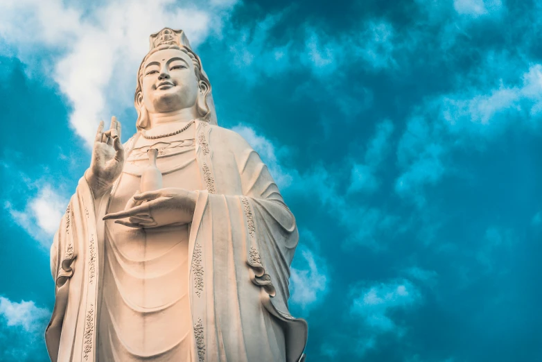 the white statue is near a cloudy blue sky