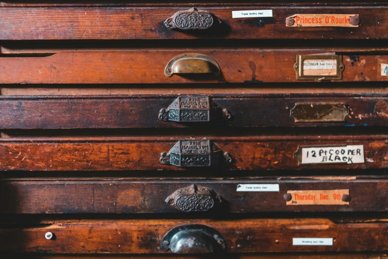 several antique wooden drawer with tags on them