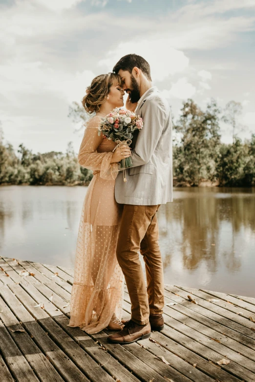 a couple poses for a picture on the dock at a lake