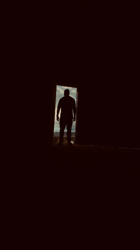 silhouette of man with open door in dark room