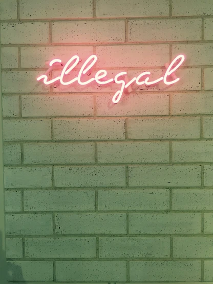 a pink neon sign is on the brick wall