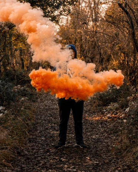 the person is standing on a path holding onto the colorful substance