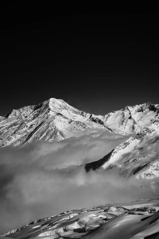 snow covered mountains on a dark day with white clouds