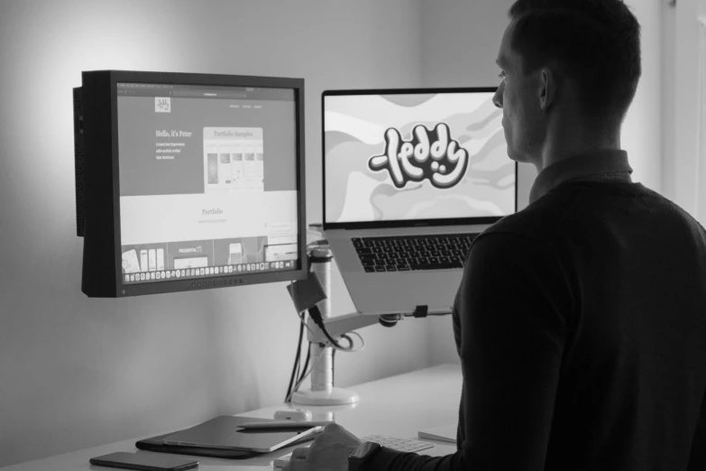 a man standing in front of two monitors on a desk