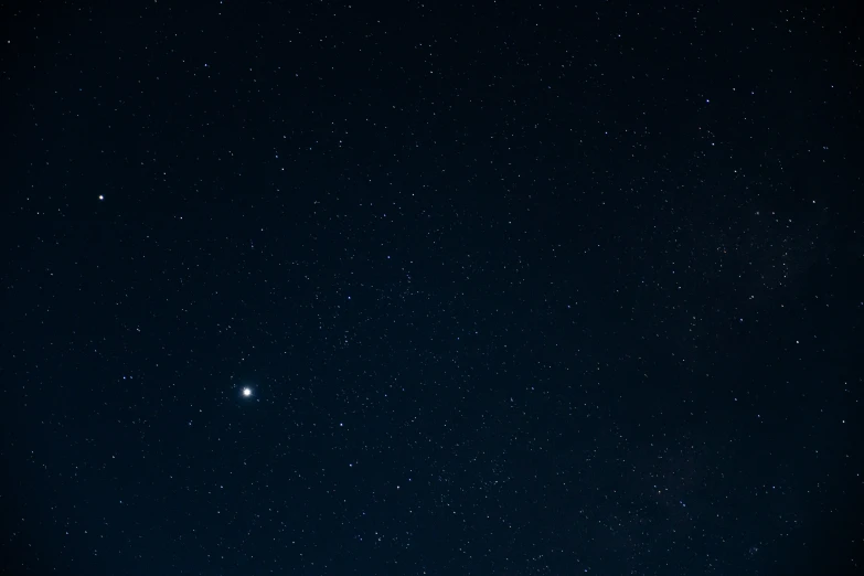 two people standing together in the distance as they look at stars