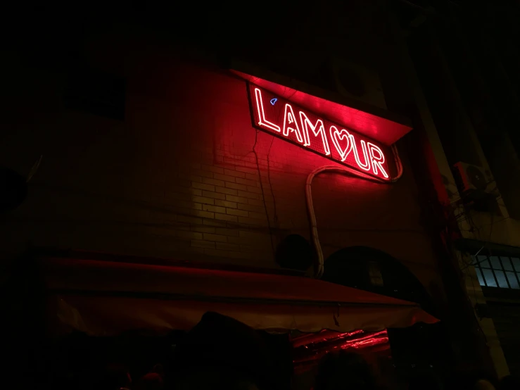 a bright red neon sign with the word glamour lit up in the dark