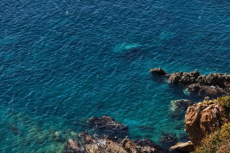 the view from above of a cliff and some blue water