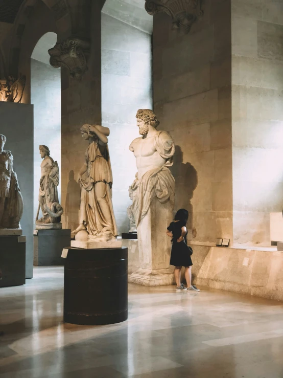 the person is standing near statues that are on display