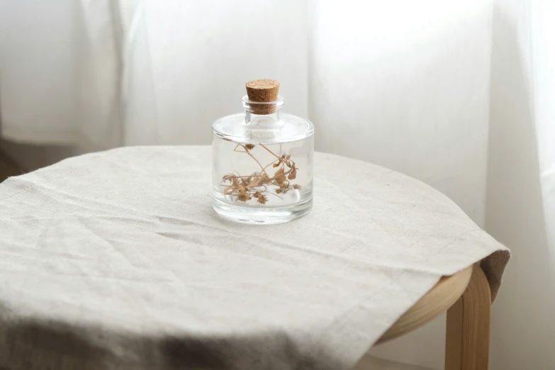 a round table with a bottle and some dried flowers