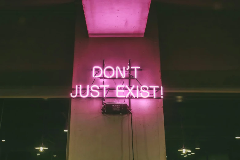 a neon sign on a building reads don't just exit