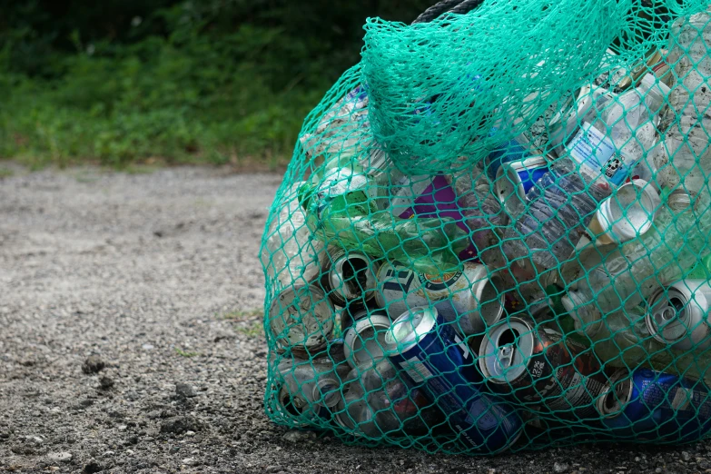 a bag full of beer cans sits in the sand