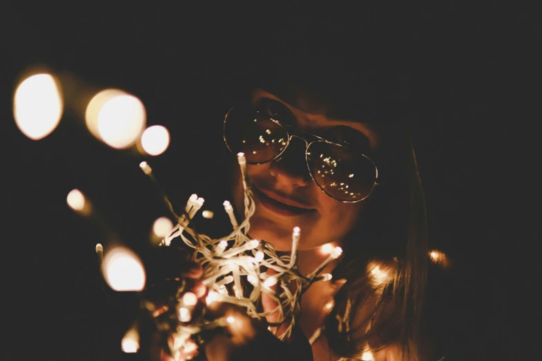 the girl is holding the bunch of christmas lights