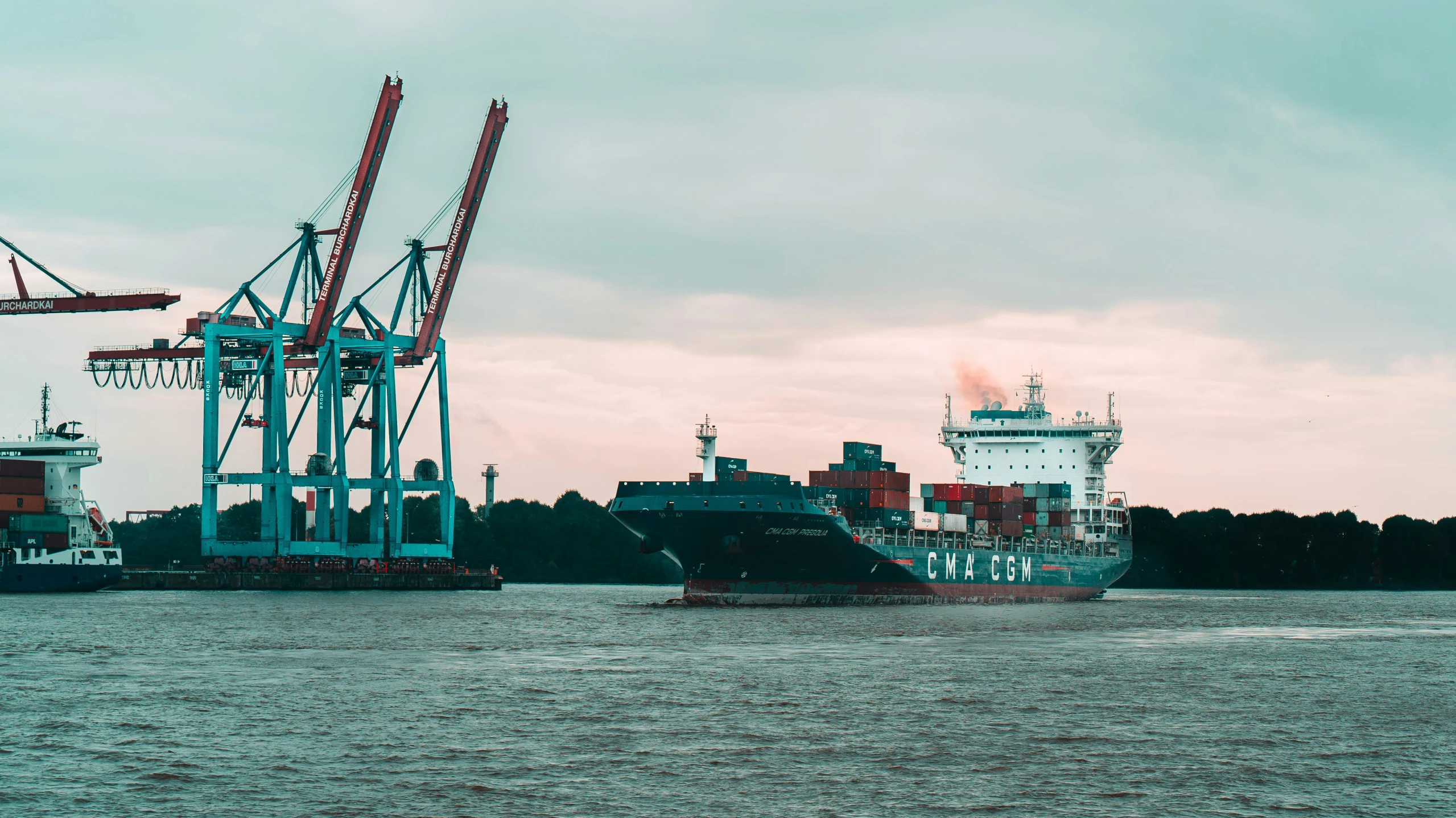 a boat moving past two big cargo ships