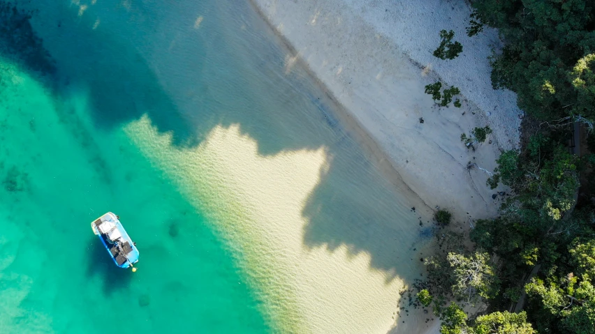 an aerial view of a boat in the crystal clear waters