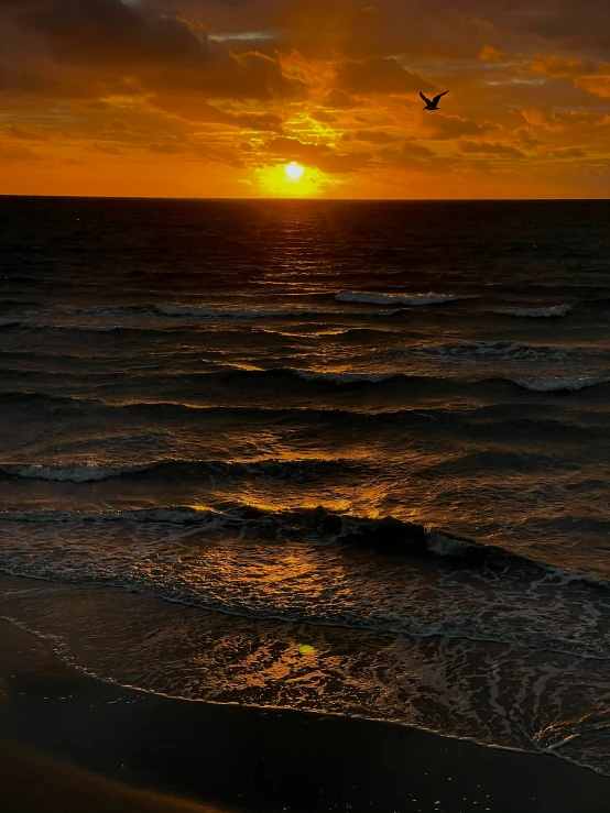 the sun setting over the ocean with an orange sky