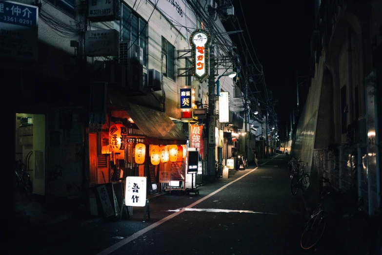a narrow alley with lights and signs at night
