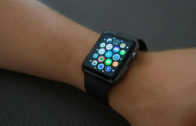 a person holding an apple watch with the screen covered in icons