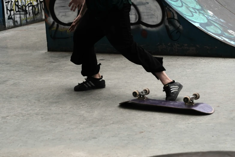 a person with black shoes on is standing in front of a skateboard