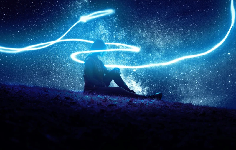 a man is sitting under the stars in the sky with blue light