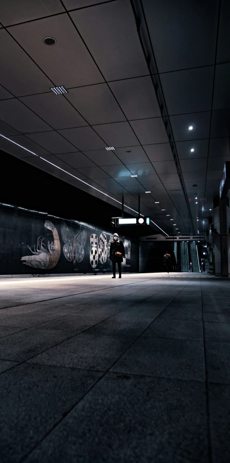 a person is walking down an empty and dark subway