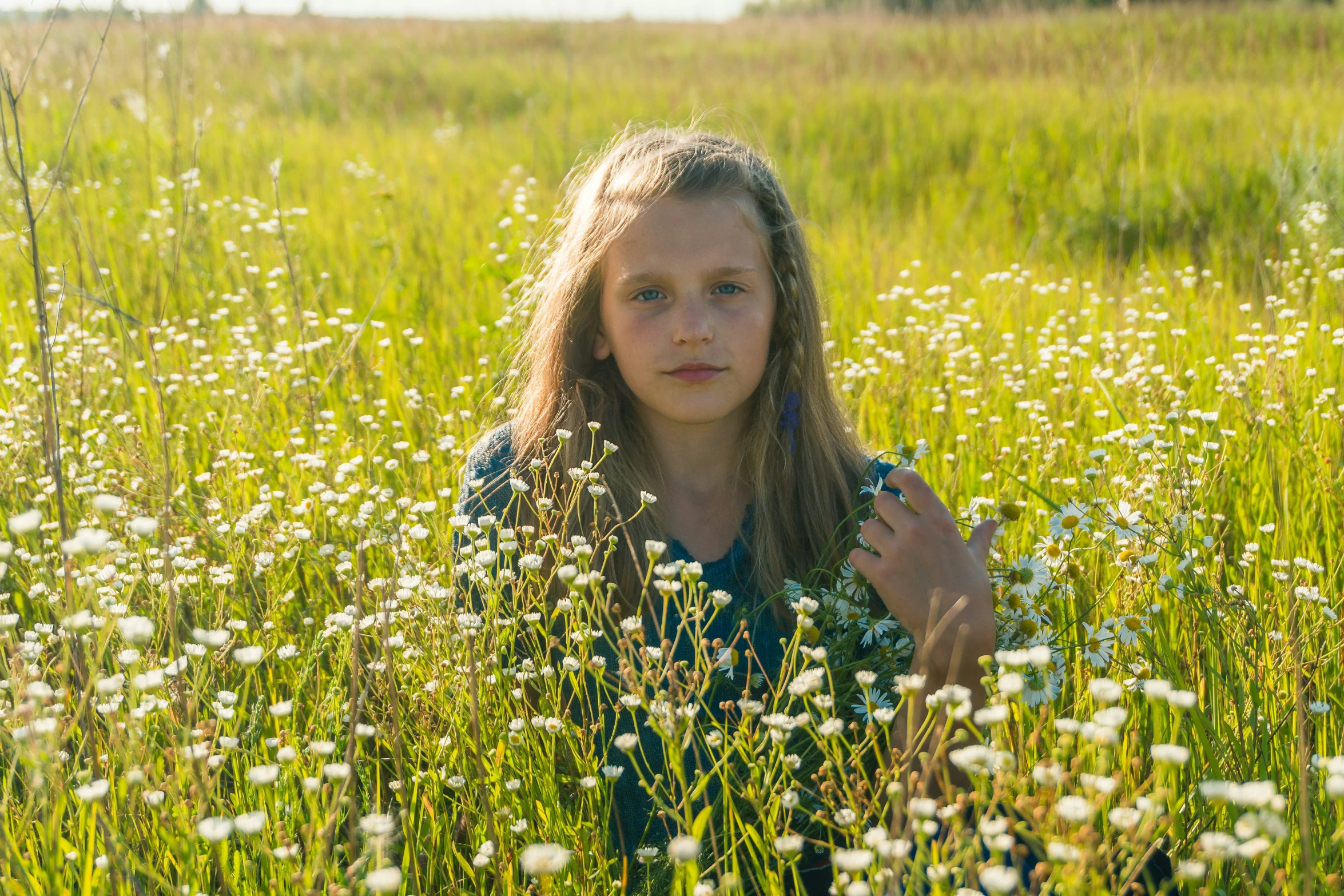 a girl is sitting in the middle of tall grass