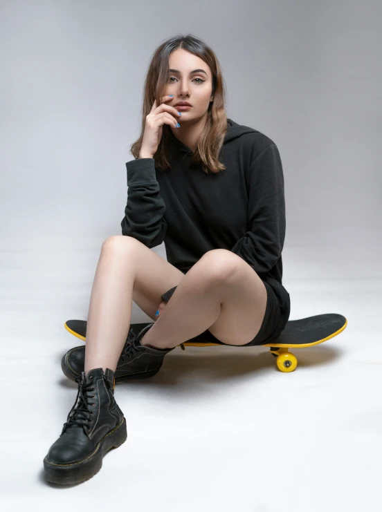 young woman sitting on a skateboard posing for a picture