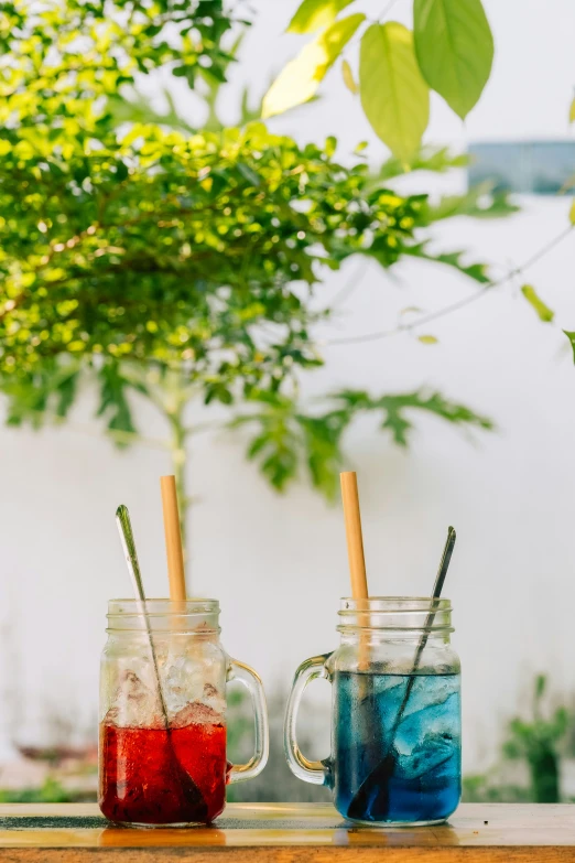 two mason jar with drinks filled with liquid and straws