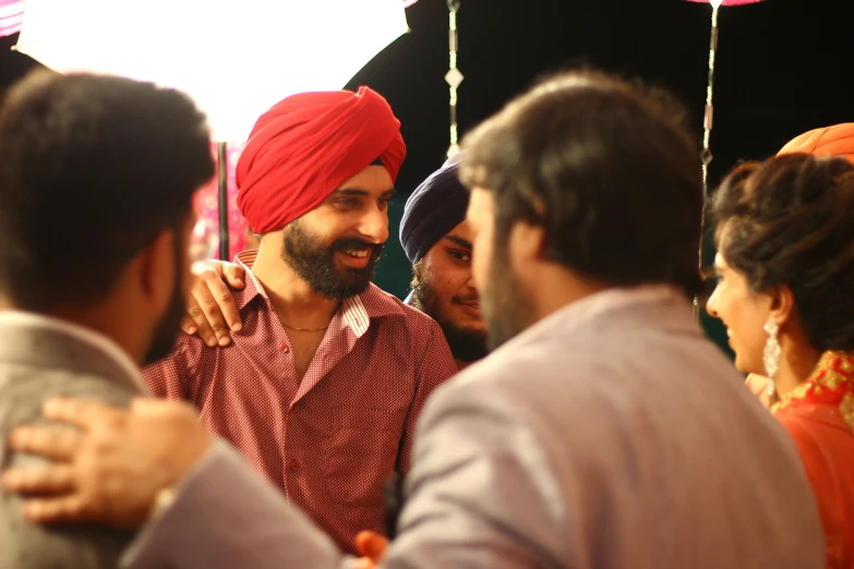 a man smiles as his friends chat