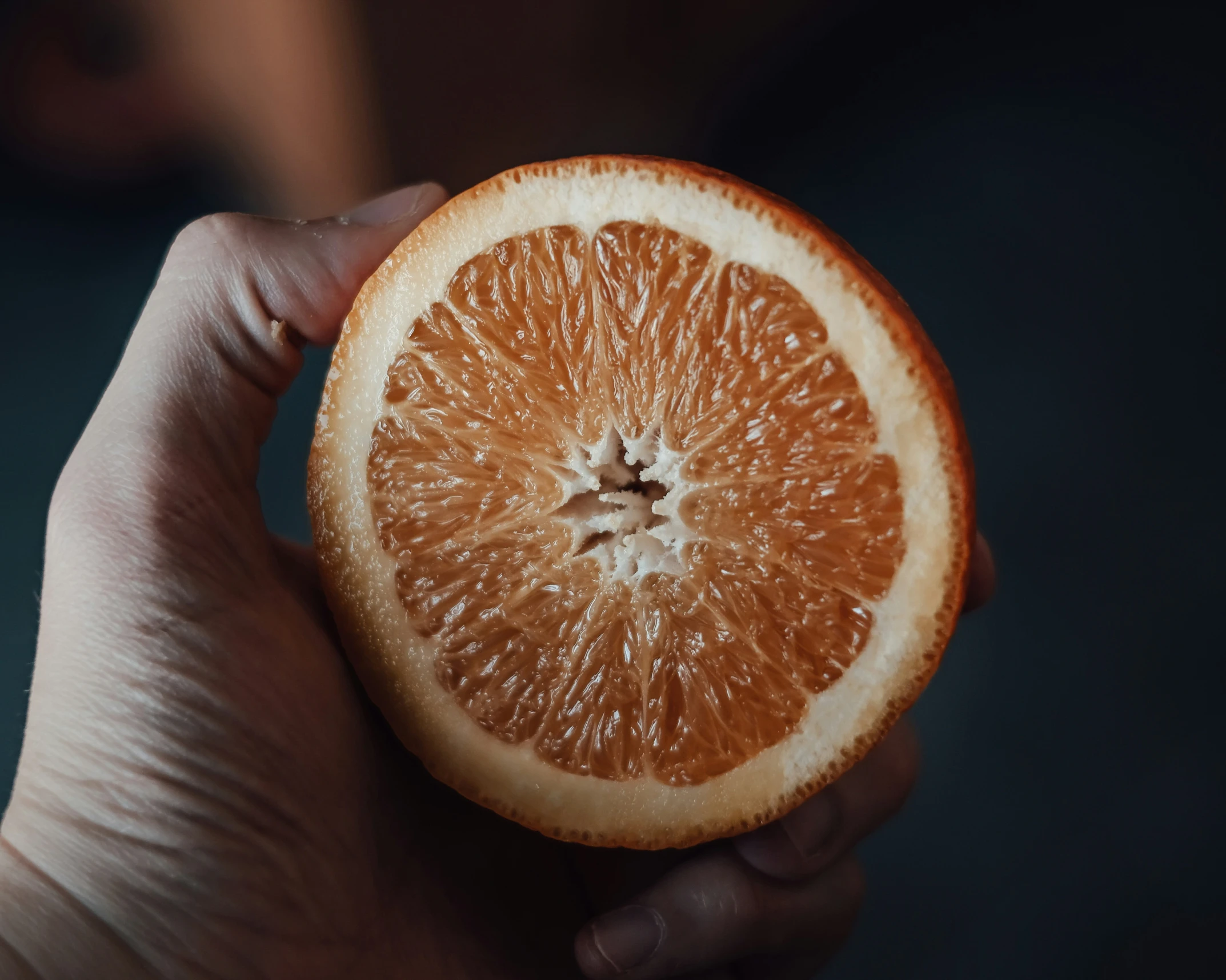 a person holding an orange up to their face
