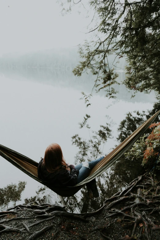 the person is in a hammock by the water