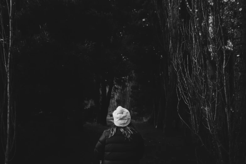 black and white pograph of woman walking through woods