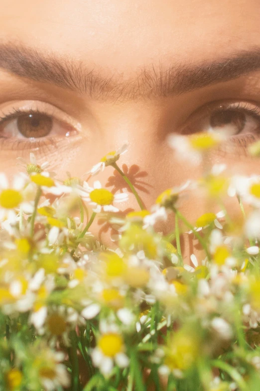 a young woman looking at the camera with flowers in front of her