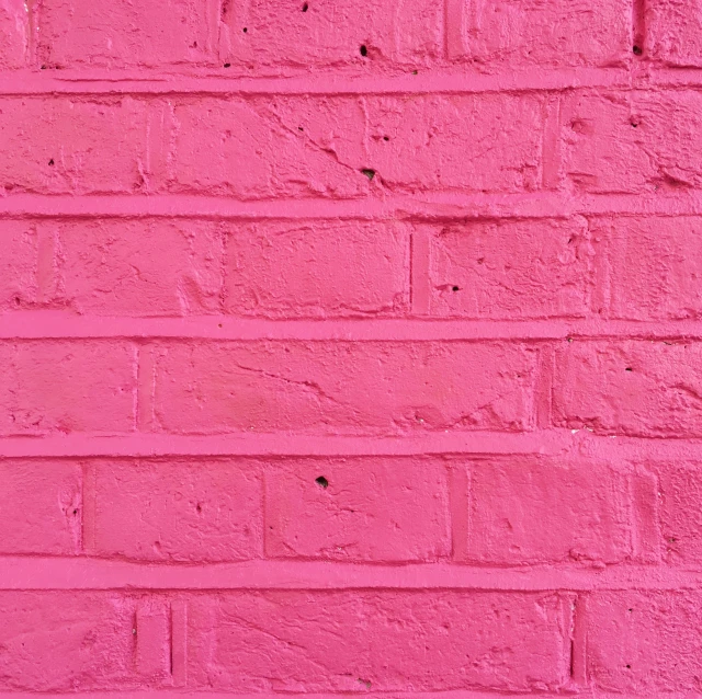 a very tall pink brick wall next to a small fence