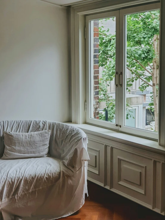 a white couch sitting in front of a window with a pillow on top of it