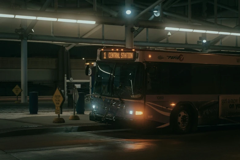 a big bus with headlights on parked at the side of a street