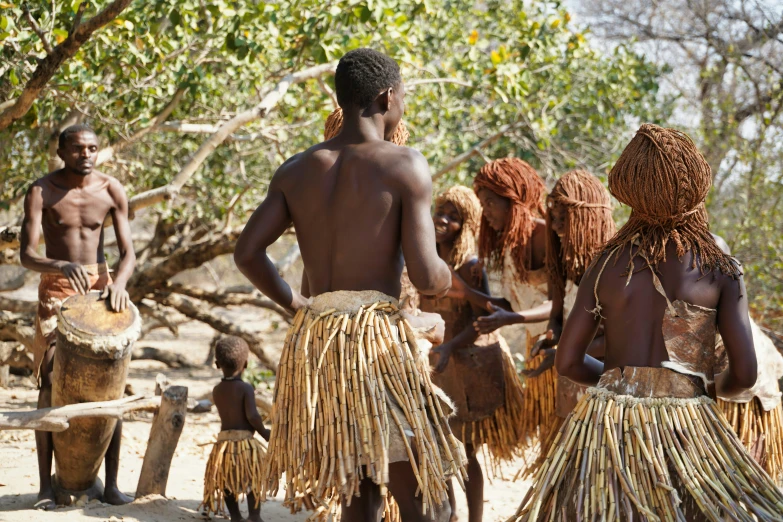 a group of men and women dancing in front of trees