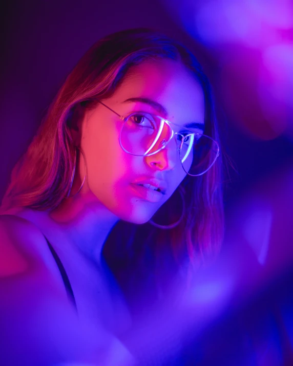 a girl in glasses looking at the camera with blue light